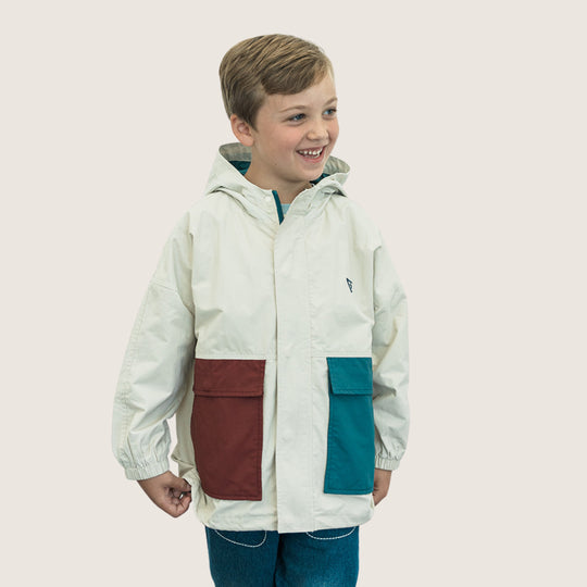 Child wearing an ivory Colorblock Hooded Jacket with burgundy and teal front pockets, showing the hood, cuffs and full hem.