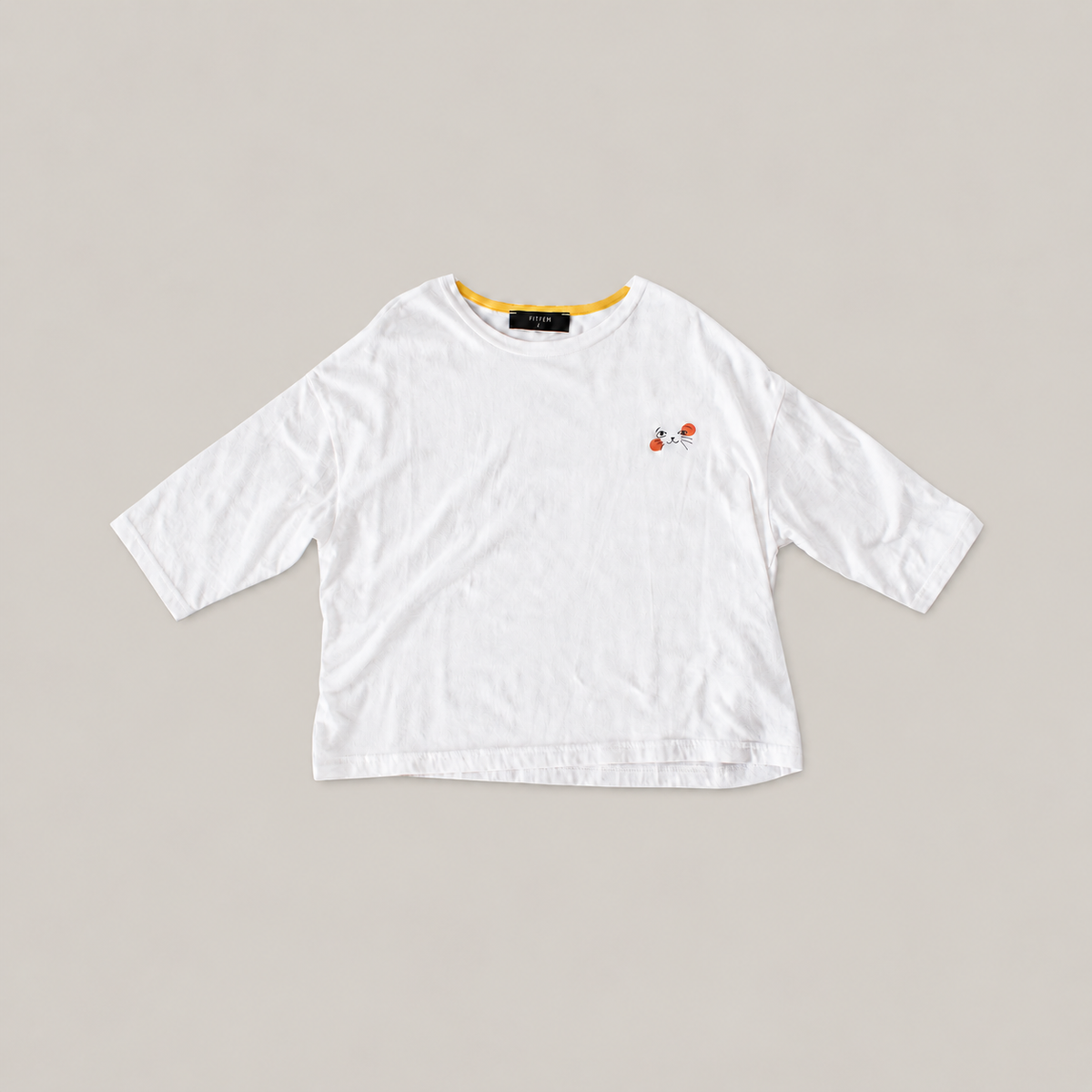 White Cat Nap Tee with relaxed sleeves, yellow inner neckline and a small black cat face with orange accents.