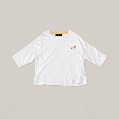 White Cat Nap Tee with relaxed sleeves, yellow inner neckline and a small black cat face with orange accents.