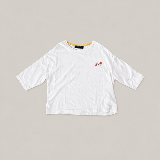 White Cat Nap Tee with relaxed sleeves, yellow inner neckline and a small black cat face with orange accents.