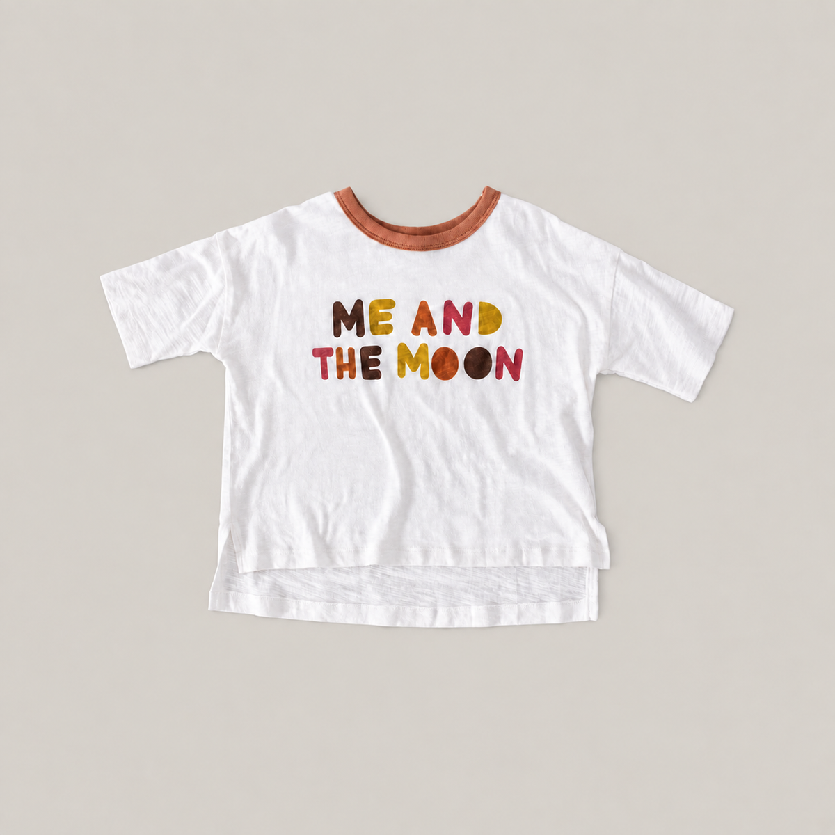 White Luna Graphic Tee with a brown neckline, colorful ME AND THE MOON lettering and a longer back hem.