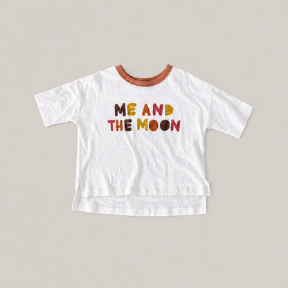 White Luna Graphic Tee with a brown neckline, colorful ME AND THE MOON lettering and a longer back hem.