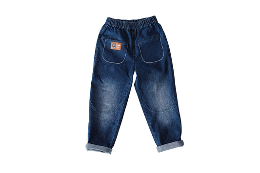 The Every Pant is shown flat in dark blue denim with white pocket stitching, a brown patch and rolled cuffs.