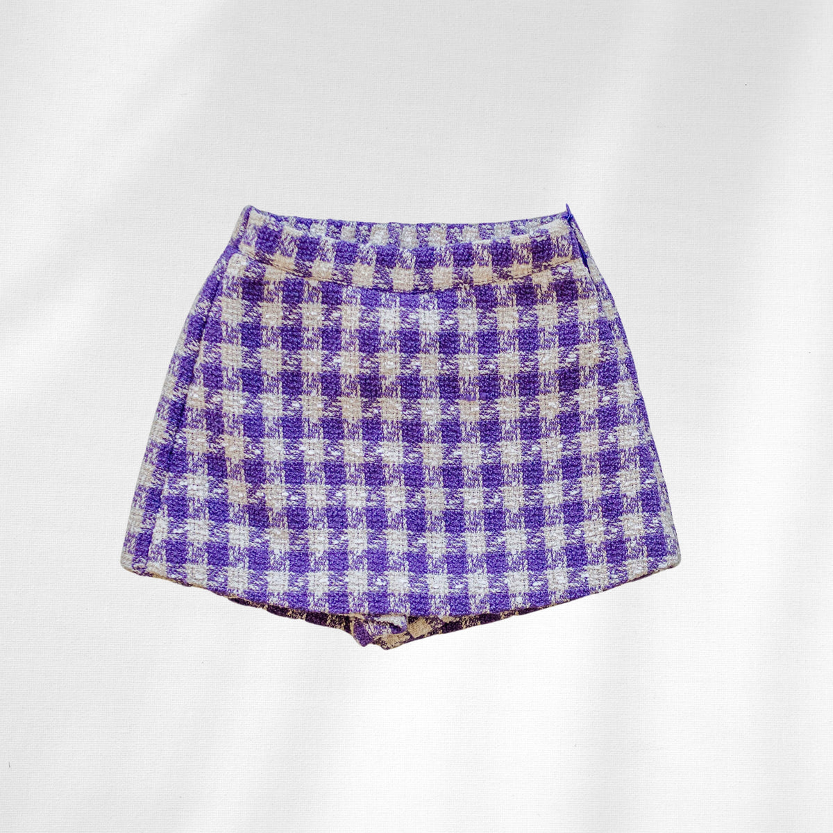 The Uptown Girl Skort is shown flat with purple-and-cream checks and shorts visible beneath the front skirt panel.