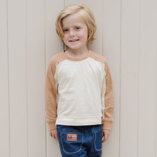 Child wearing the Modern Rugby Tee, showing its ivory body, camel long sleeves and relaxed fit.